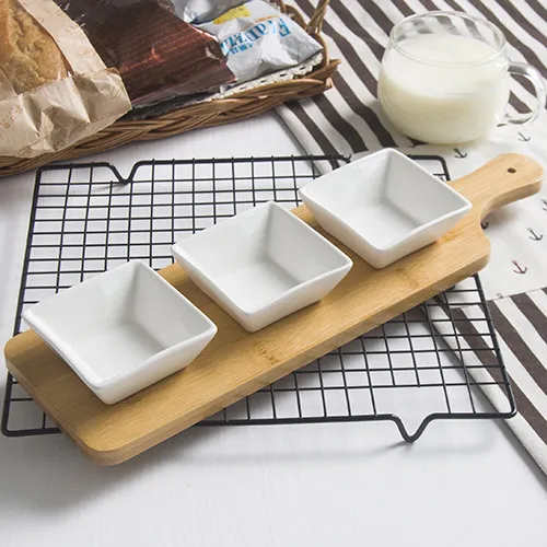 Bandeja dividida de bambú para servir con platos de cerámica blanca, cuencos para aperitivos y dulces